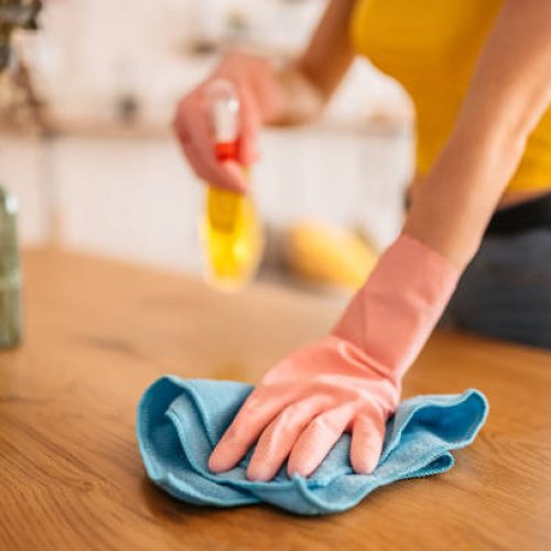 young beautiful woman tidying up the living room and wiping the dining table surface with a cloth.